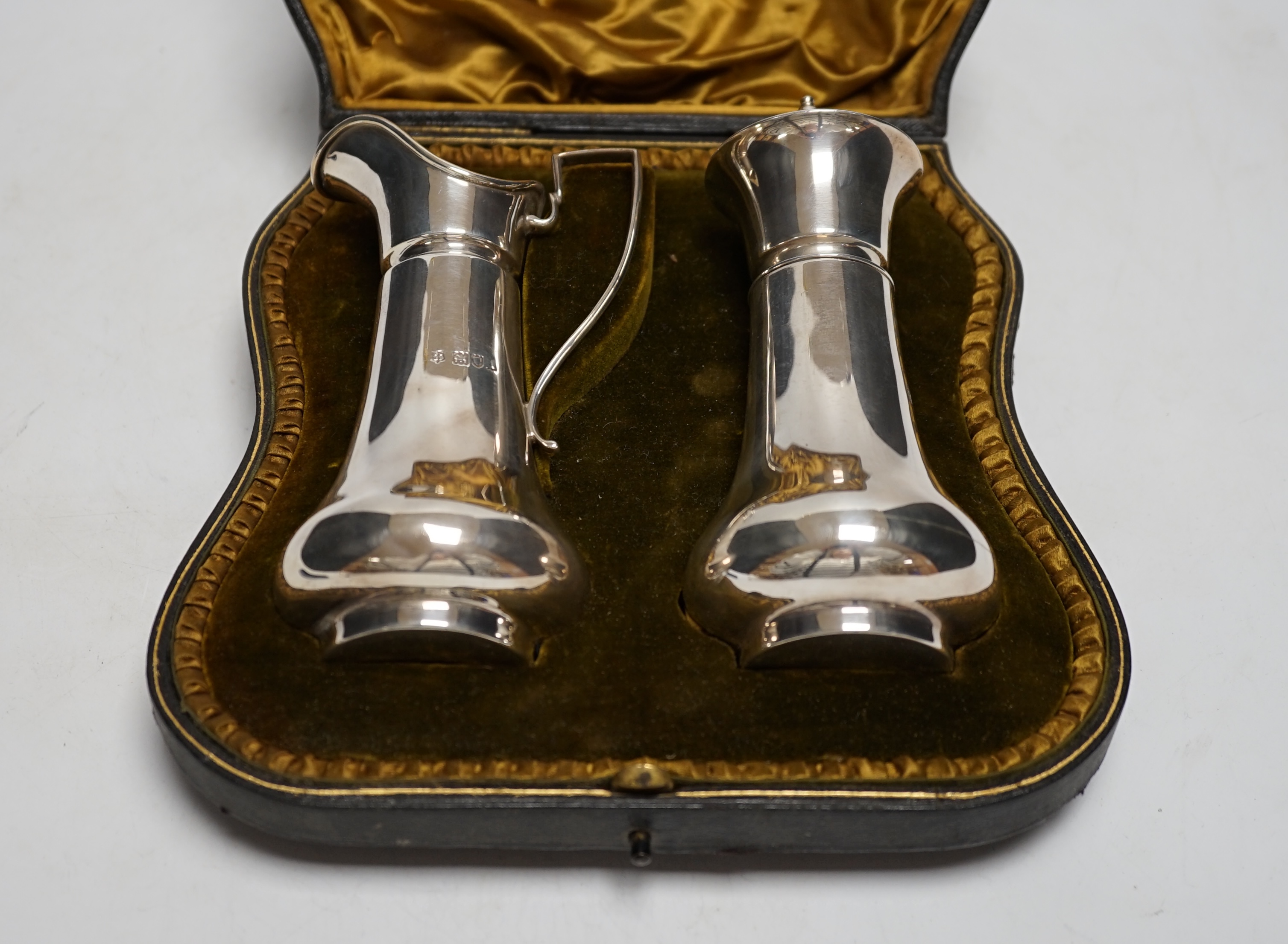 An Edwardian cased silver strawberry and cream set, comprising a cream jug and sugar sifter, by Josiah Williams & Co, London, 1906, jug height 13.4cm, 8.5oz.